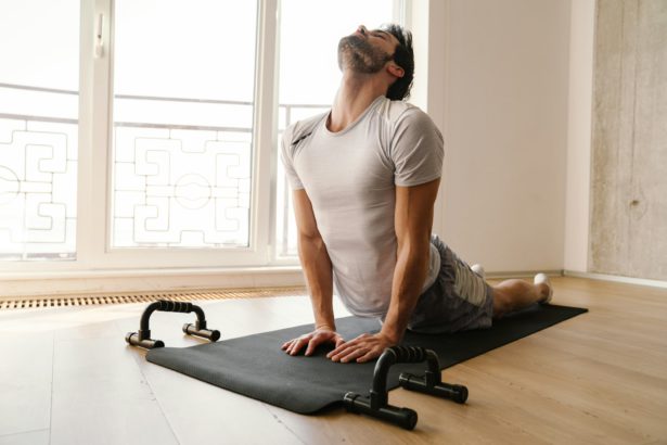 Focused athletic man stretching his body while working out at home