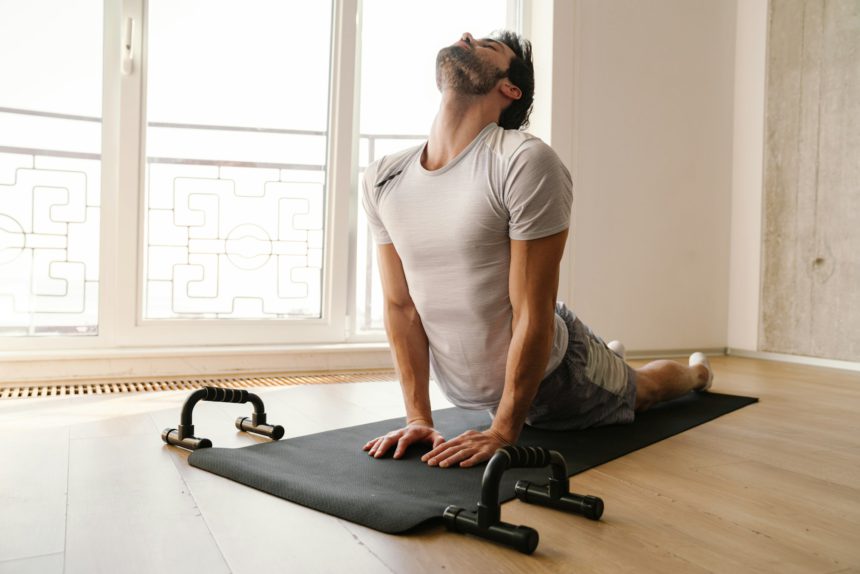 Focused athletic man stretching his body while working out at home